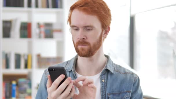 Casual pelirroja hombre usando teléfono inteligente — Vídeo de stock