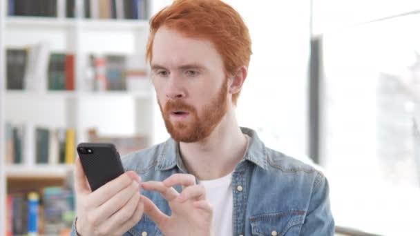 Casual Redhead man chockad av resultat på telefon — Stockvideo