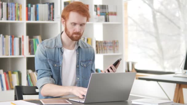Multitasking, příležitostný Redhead Man používání telefonu, tabletu a laptopu — Stock video