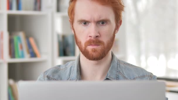 Megdöbbentette alkalmi vöröshajú ember dolgozik laptop — Stock videók