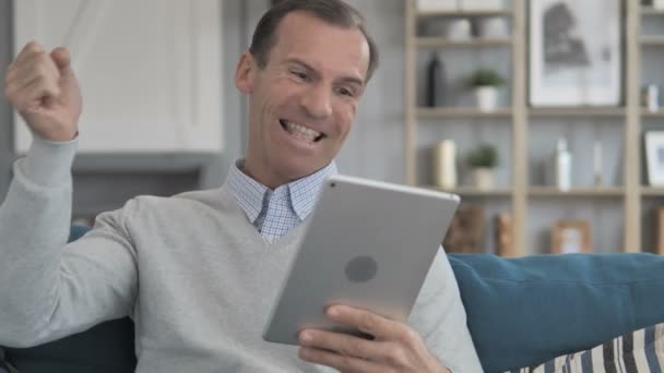 Relajante hombre de mediana edad celebrando el éxito en la tableta — Vídeo de stock