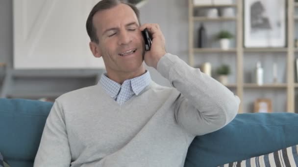 Relaxovat muže ve středním věku pomocí telefonu Smartphone při sezení na gauči — Stock video