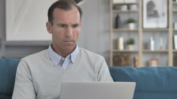 Schockierter Mann mittleren Alters fragt nach Ergebnissen auf Laptop — Stockvideo
