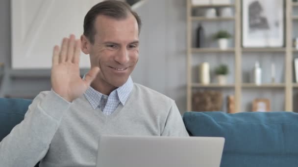 Chat de vídeo en línea en el ordenador portátil por el hombre de mediana edad sentado en el lugar de trabajo creativo — Vídeo de stock