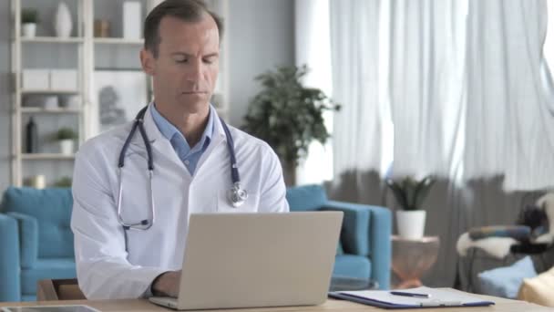 Starszy lekarz pracujący na laptopie w klinice — Wideo stockowe