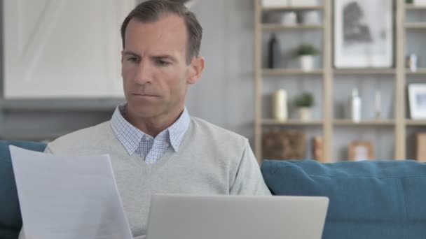 Hombre de mediana edad haciendo papeleo mientras está sentado en un espacio de trabajo creativo — Vídeo de stock