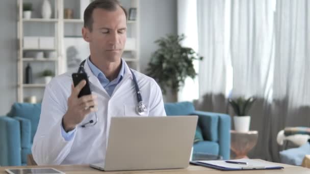 Médico sênior conversando por telefone com paciente na clínica — Vídeo de Stock