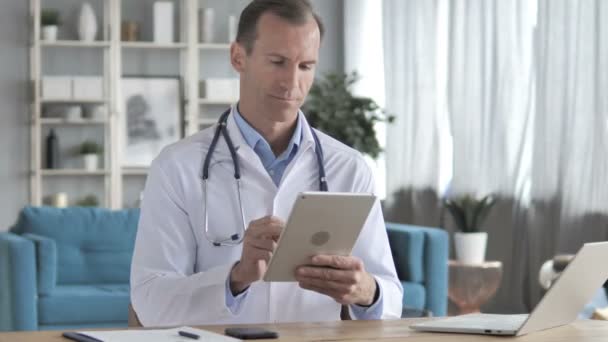 Rozmowa wideo przez tablet z pacjentem przez starszego lekarza — Wideo stockowe