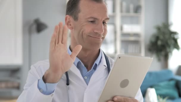 Ανώτερος γιατρός συζητώντας με τον ασθενή μέσω βιντεοσυνομιλίας στο tablet — Αρχείο Βίντεο