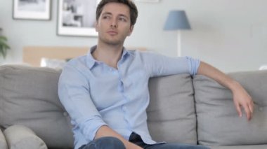 Kanepede otururken Pensive yaratıcı genç adam düşünme