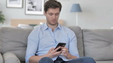 Kanepede rahatlatıcı iken telefonda konuşan genç adam