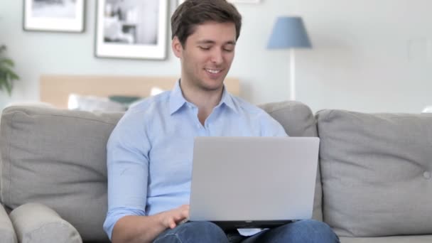 Online video chat op laptop door knappe jonge man zittend op creatieve werkplek — Stockvideo