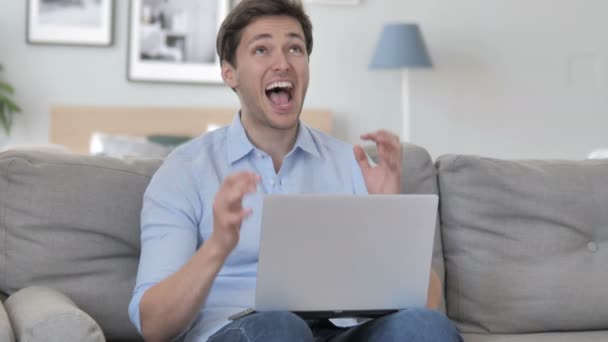 Knappe jonge man viert succes op laptop — Stockvideo