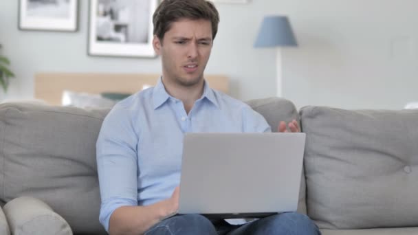 Frustrovaný muž reakce na ztrátu na přenosném počítači při sezení na gauči — Stock video