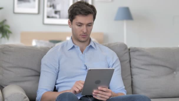 Guapo joven hojeando Internet en la tableta — Vídeo de stock