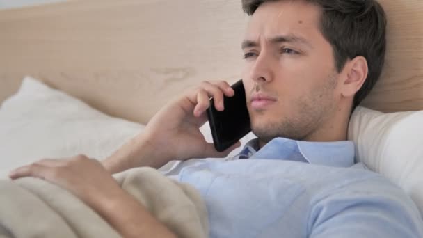 Relaxační mladík mluvící telefonem v posteli — Stock video