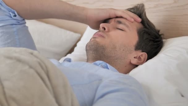 Jovem tenso com dor de cabeça deitado na cama — Vídeo de Stock