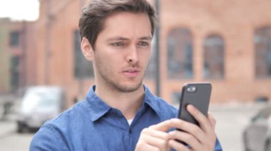 Smartphone kullanırken kayıp tarafından üzgün genç adam açık portresi