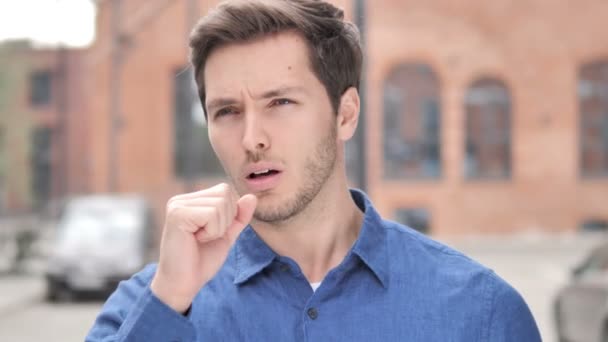 Больной молодой человек кашляет, стоя на улице — стоковое видео