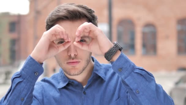 Gesto binocular hecho a mano por el joven guapo que busca una nueva oportunidad — Vídeos de Stock