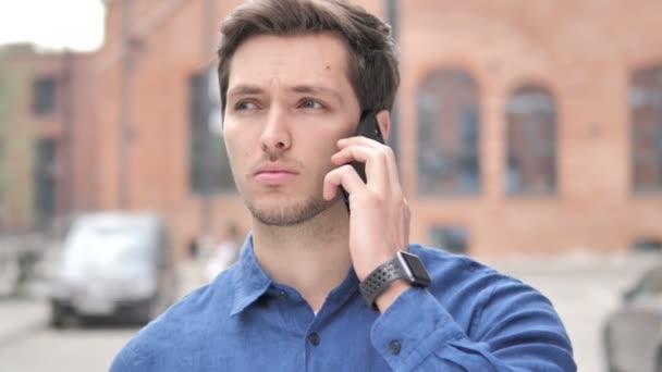 Retrato al aire libre del joven hablando por teléfono — Vídeos de Stock