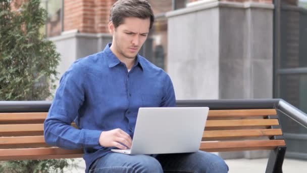 Seduto all'aperto giovane uomo con mal di schiena lavorando sul computer portatile — Video Stock