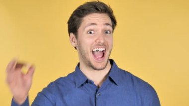 Sarı arka planda Casual genç adam tarafından Tamam jest