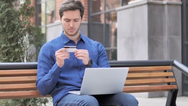 Покупки в Интернете, молодой человек сидит на скамейке — стоковое видео