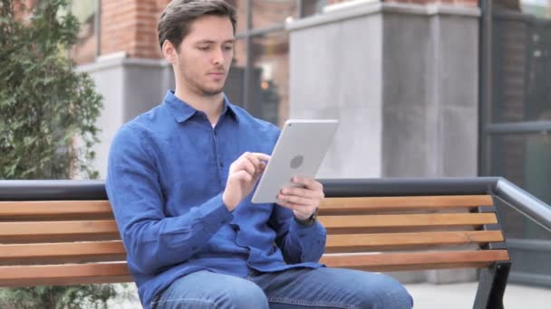 Άνθρωπος επευφημίες για την επιτυχία στο tablet, ενώ κάθονται στο πάγκο — Αρχείο Βίντεο