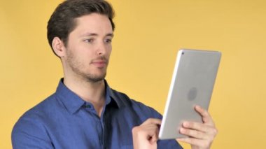 Sarı arka planda tablet kullanarak Casual genç adam