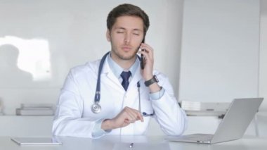 Genç doktor telefonda hasta ile konuşan