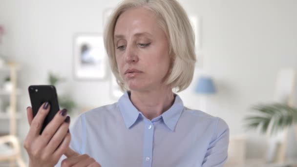 Cheering oude vrouw enthousiast voor succes op smartphone — Stockvideo