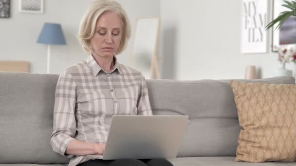 Ηλικίας γυναίκα χρησιμοποιώντας φορητό υπολογιστή ενώ κάθεται στον καναπέ — Αρχείο Βίντεο