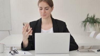 Akıllı telefon ve dizüstü bilgisayar kullanarak multitasking genç Businesswoman
