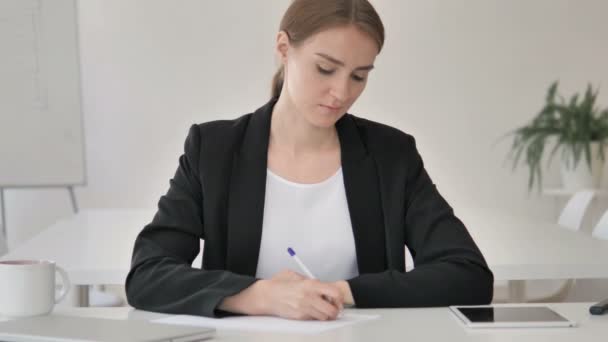 Junge Geschäftsfrau schreibt auf Papier — Stockvideo