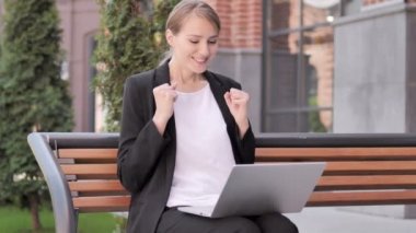 Genç Businesswoman ofis dışında oturan laptop kutluyor