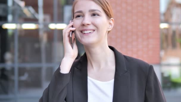 Jonge zakenvrouw praten over telefoon buiten — Stockvideo