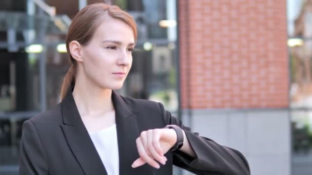 Wartende junge Geschäftsfrau kontrolliert die Uhrzeit — Stockvideo