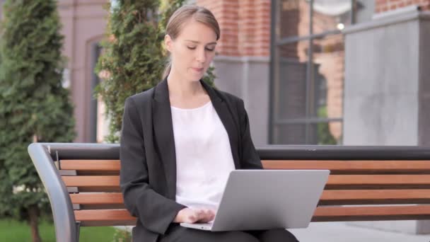 Joven empresaria trabajando en el ordenador portátil, sentada al aire libre en el banco — Vídeos de Stock