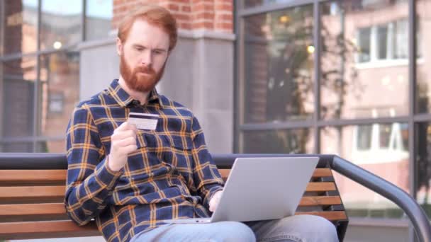 Fracaso de compras en línea para el joven pelirrojo de la barba sentado en el banco — Vídeo de stock