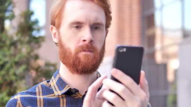 Hombre usando Smartphone mientras está sentado al aire libre — Vídeo de stock