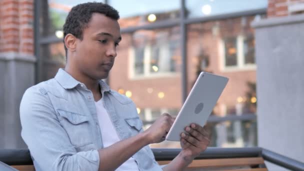 Homme africain assis en plein air et en utilisant une tablette — Video