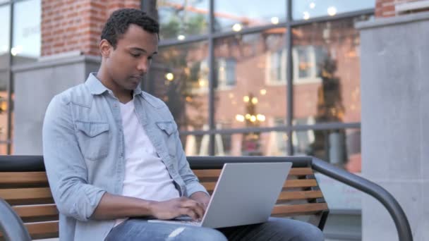 Homme africain tousse tout en travaillant sur ordinateur portable en plein air — Video