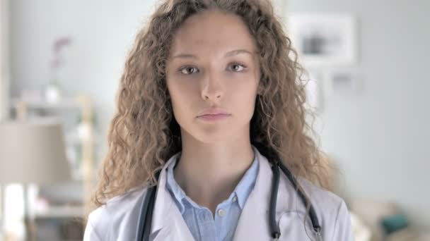 Νεαρή κυρία γιατρός στην κλινική κοιτάζοντας κάμερα — Αρχείο Βίντεο