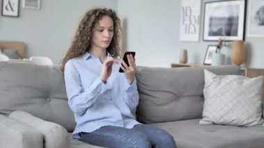 Akıllı telefon kullanarak genç kıvırcık saç kadın rahatlatıcı