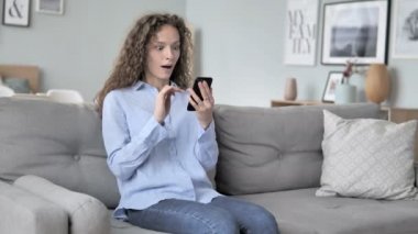 Rahatlatıcı kıvırcık saç kadın akıllı telefonda başarı tezahürat