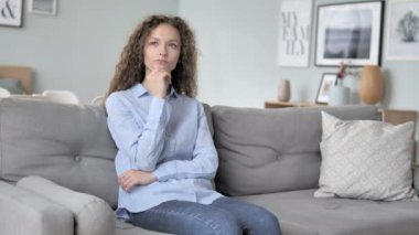 Kanepede otururken Pensive kıvırcık saç kadın düşünme