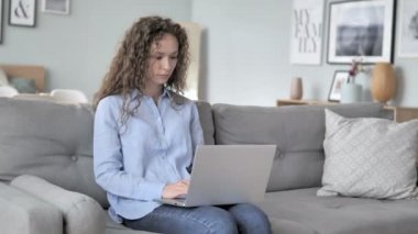 Kanepede otururken baş ağrısı laptop üzerinde çalışan kıvırcık saç kadın