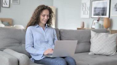 Creative Workplace oturan kıvırcık saç kadın tarafından Laptop Online görüntülü sohbet