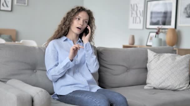 Junge Frau mit lockigem Haar telefoniert beim Entspannen auf dem Sofa — Stockvideo